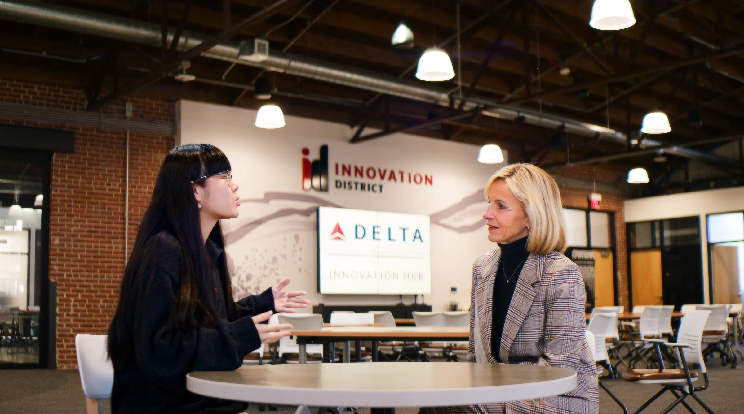 Two women sitting at a table engaged in conversation in the Delta Innovation Hub.
