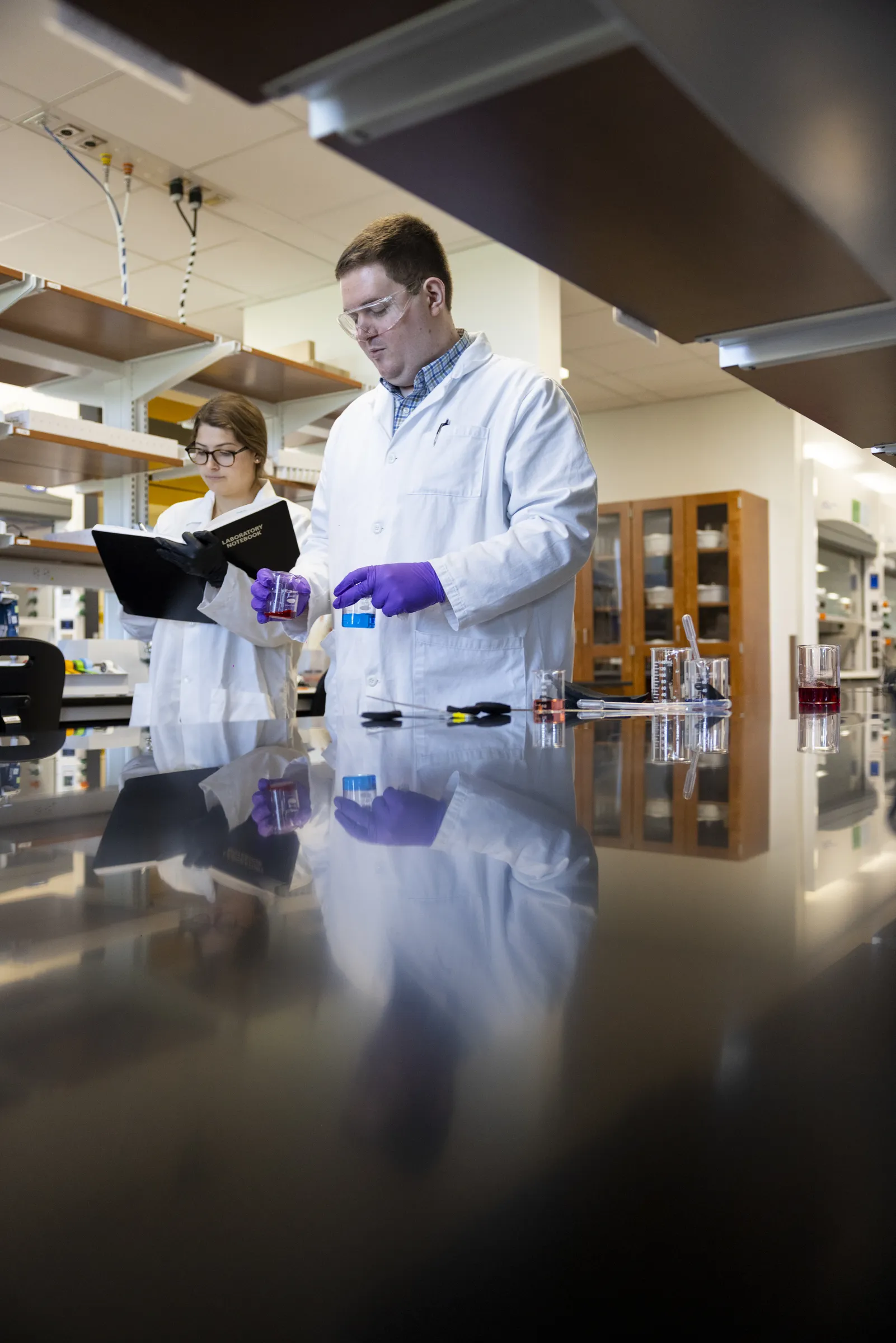 People in lab coats conducting experiments inside a lab.