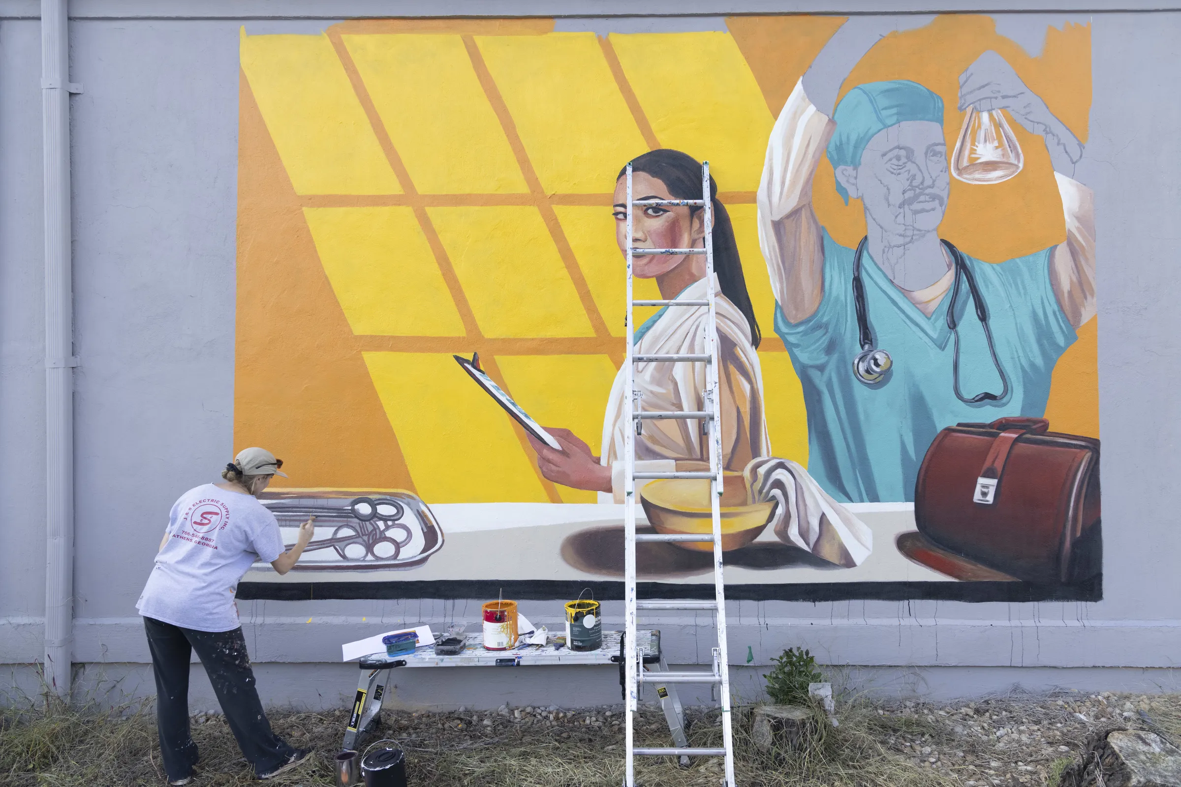A painter putting the finishing touches on a colorful mural on the side of a building.