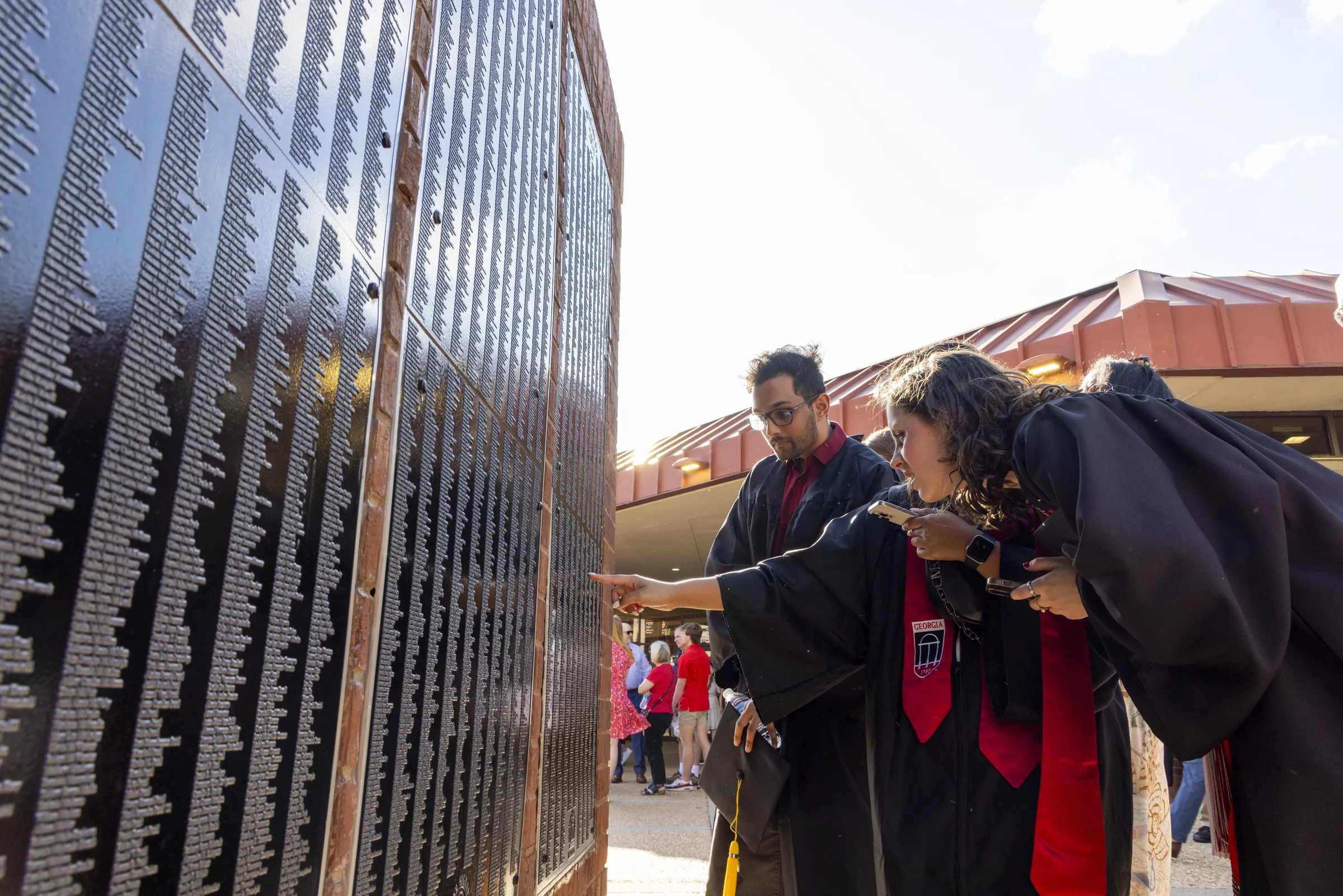 Undergraduate students search for their names on the Class of 2024 Senior Signature plaque in Tate Plaza.